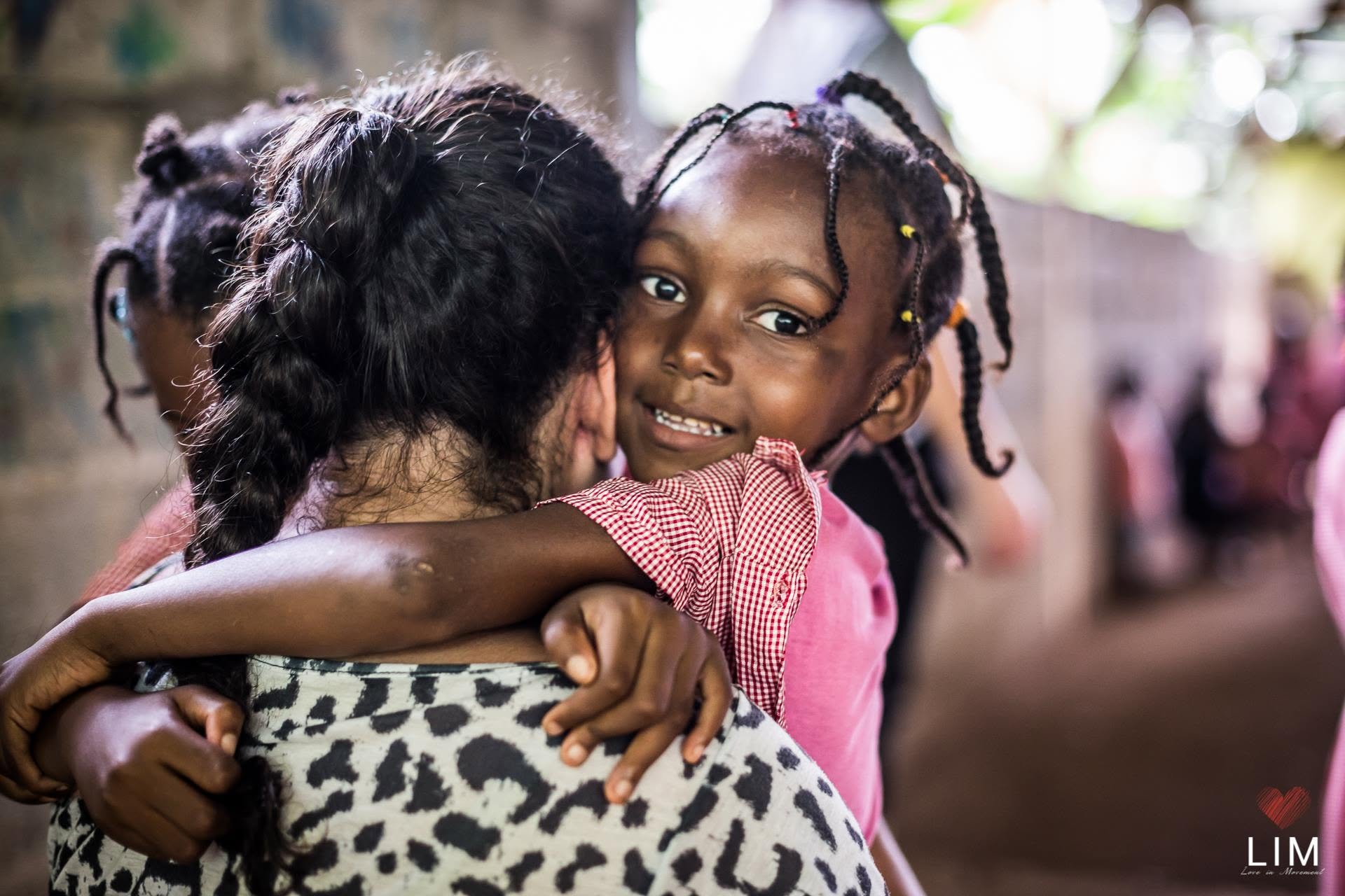 Criança sorrindo abraçada a uma voluntária